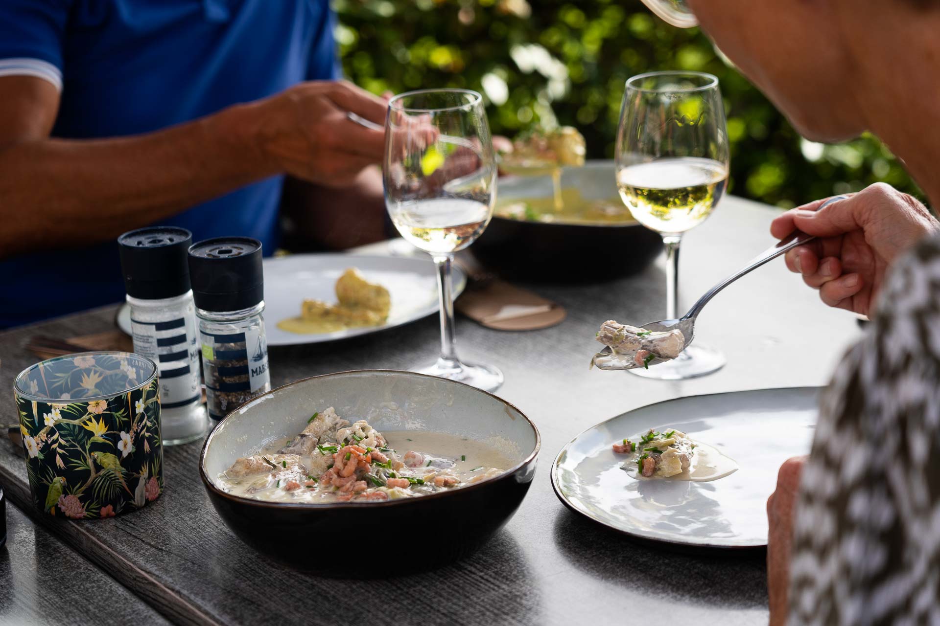 zomers sfeerbeeld van het zonovergoten terras van restaurant Roste Muis in Waterland-Oudemand bekend om z’n palinggerechten. Het restaurant bevindt zich aan Oudemanskreek vlakbij het bekende kunstwerk van Chris Ferket met de naam “Als de vos de passie preekt boer let op uw ganzen.” Het kunstwerk  staat symbool voor het Meetjeslandse krekengebied.